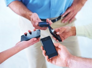 Cropped shot of four businesspeople putting their smartphones together