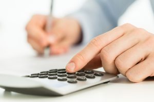 Close-up of a man's hand on a calculator.