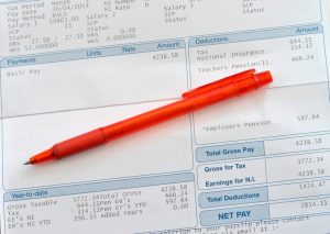 A scool teachers wages slip section with a red coloured pen laying accros the page.